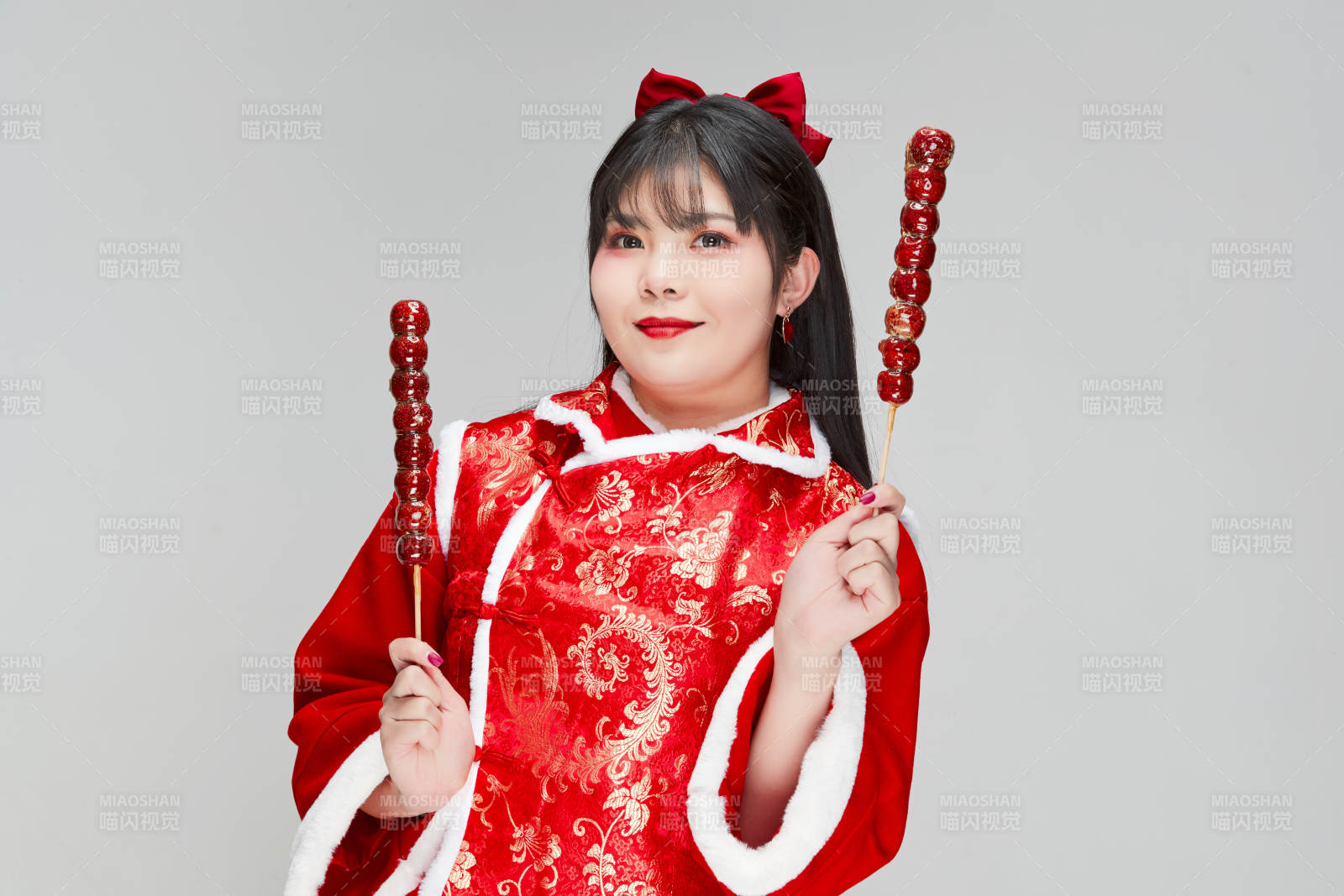 身穿喜庆服饰手拿糖葫芦吃的可爱亚洲少女图片