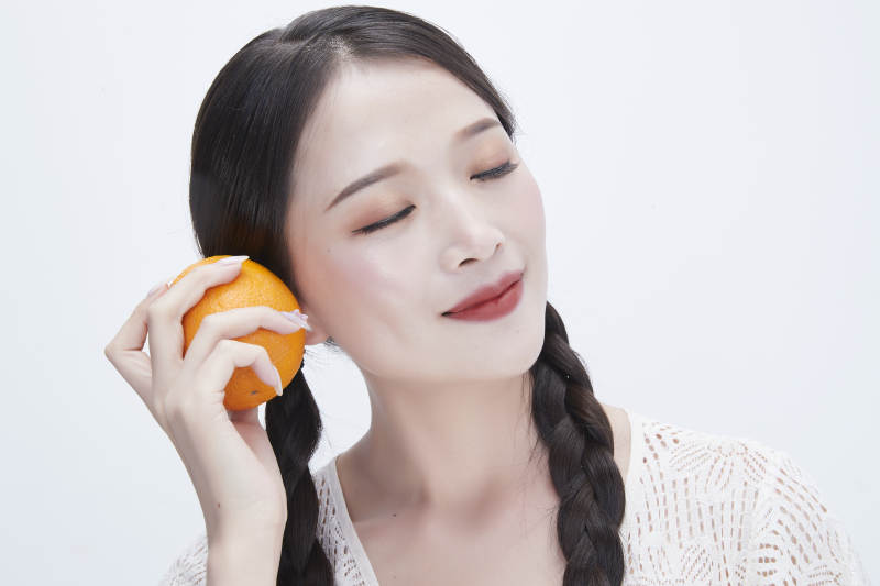 手拿橙子身穿镂空连衣裙的亚洲可爱少女人像图片