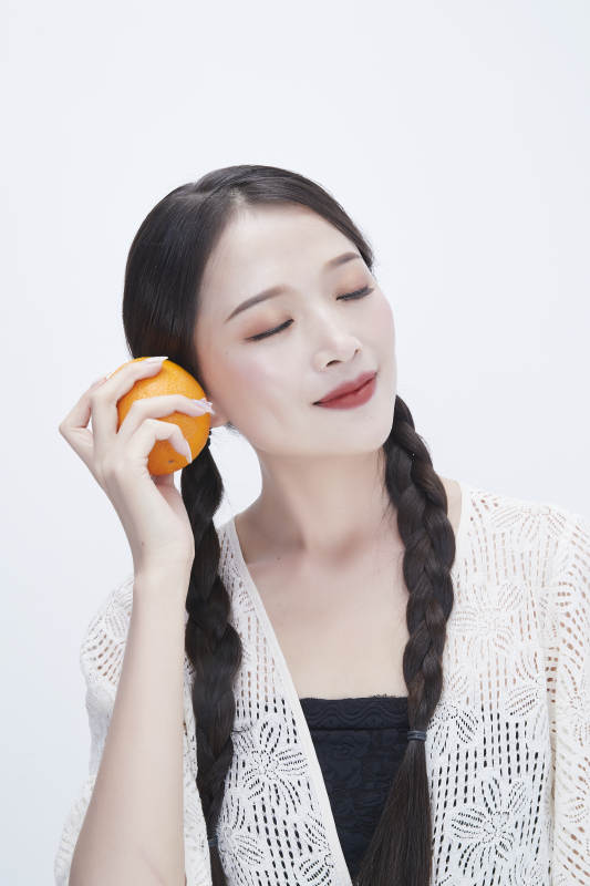 手拿橙子身穿镂空连衣裙的亚洲可爱少女人像图片
