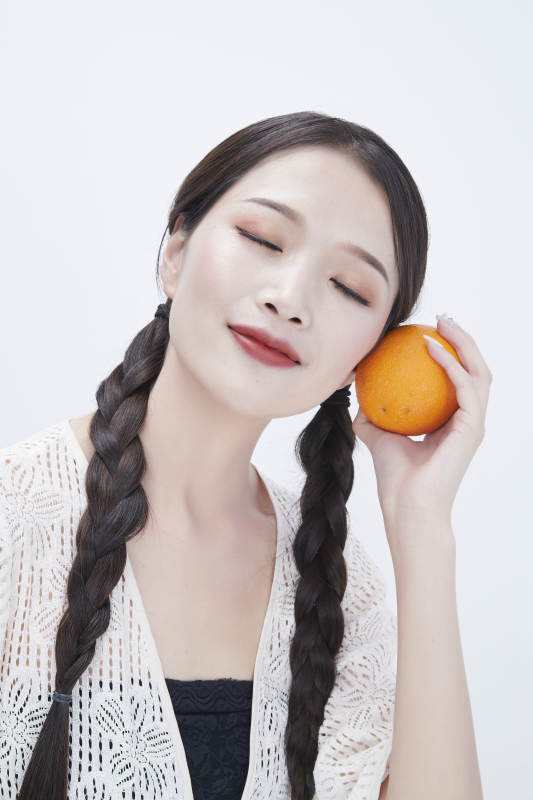 手拿橙子身穿镂空连衣裙的亚洲可爱少女人像图片