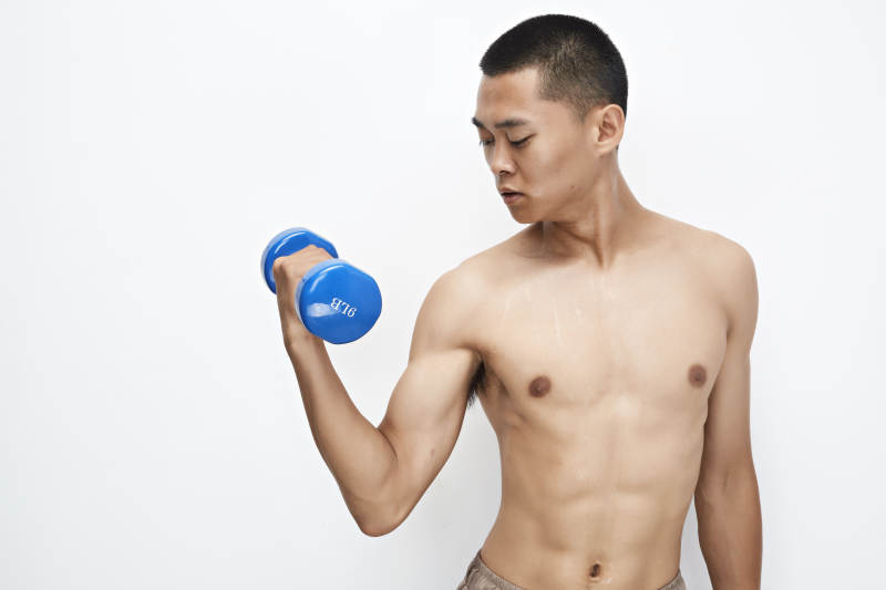 使用哑铃进行健身锻炼的亚洲男性图片