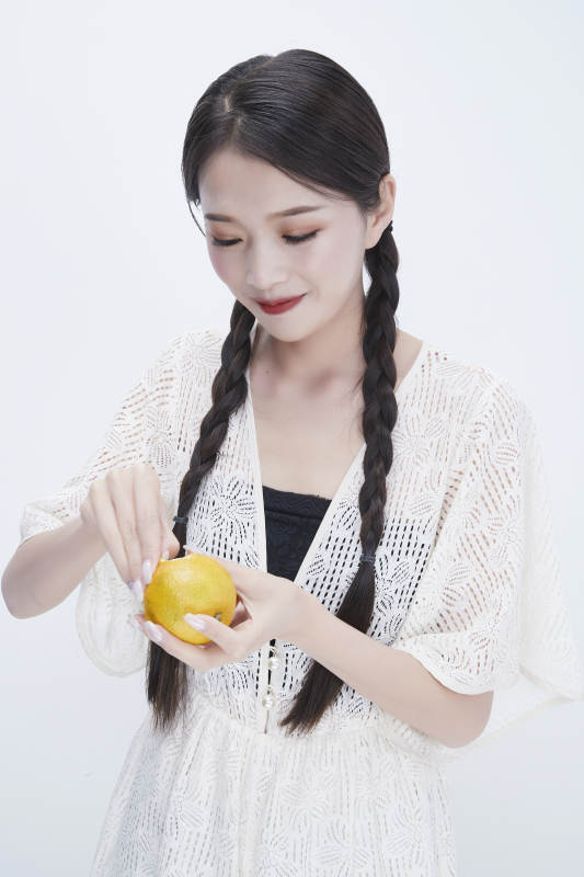 在剥橙子皮的身穿镂空连衣裙的亚洲少女人像图片