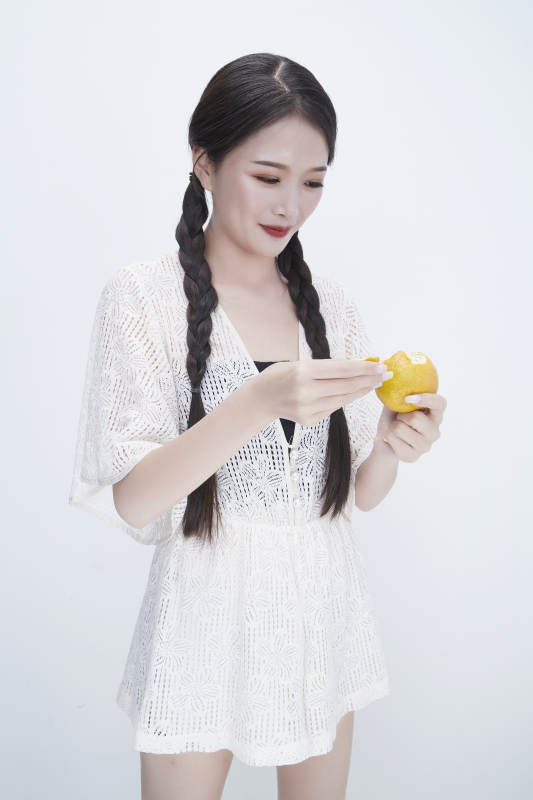 在剥橙子皮的身穿镂空连衣裙的亚洲少女人像图片