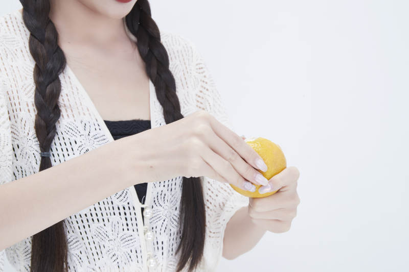 在剥橙子皮的身穿镂空连衣裙的亚洲少女人像图片