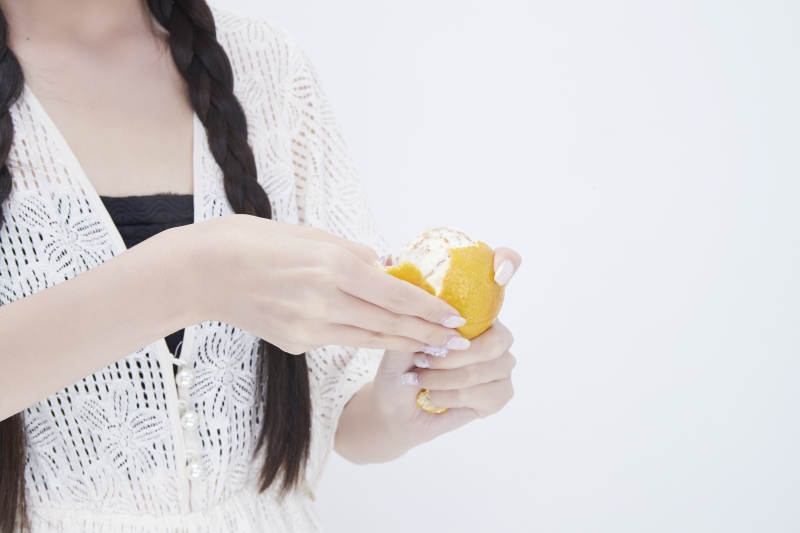 在剥橙子皮的身穿镂空连衣裙的亚洲少女人像图片