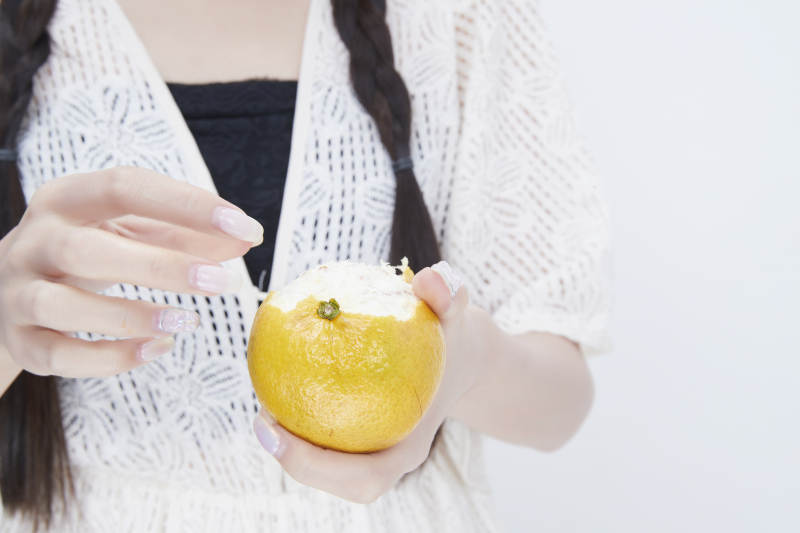 在剥橙子皮的身穿镂空连衣裙的亚洲少女人像图片