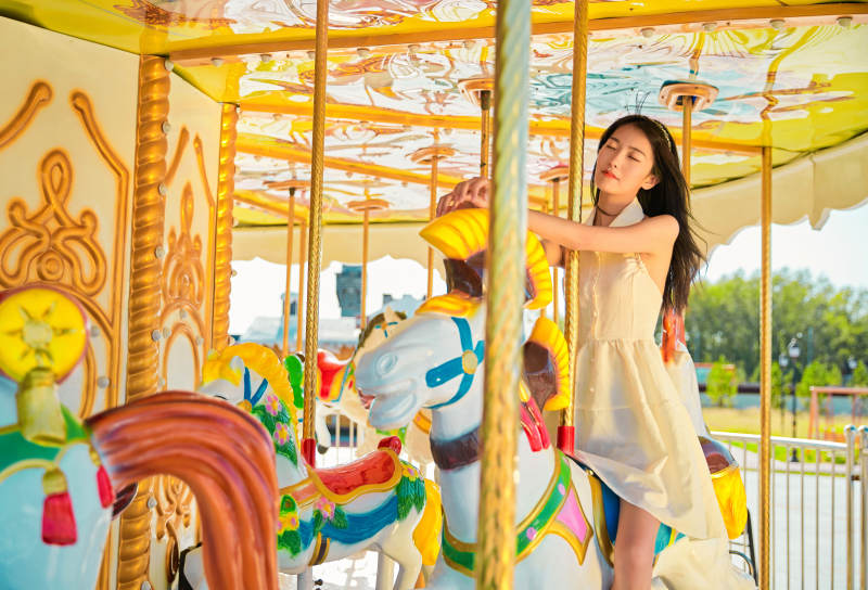 在游乐园坐旋转木马的可爱少女图片
