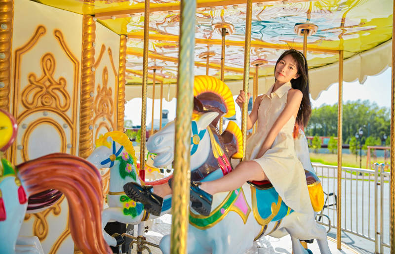 在游乐园坐旋转木马的可爱少女图片