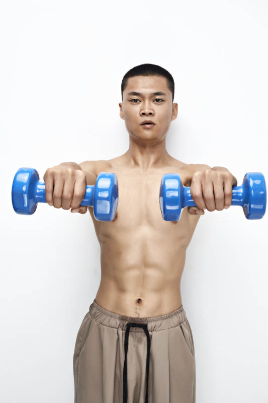使用哑铃进行健身锻炼的亚洲男性图片