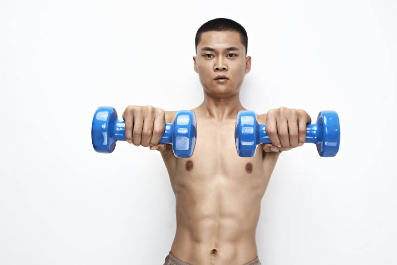 使用哑铃进行健身锻炼的亚洲男性图片