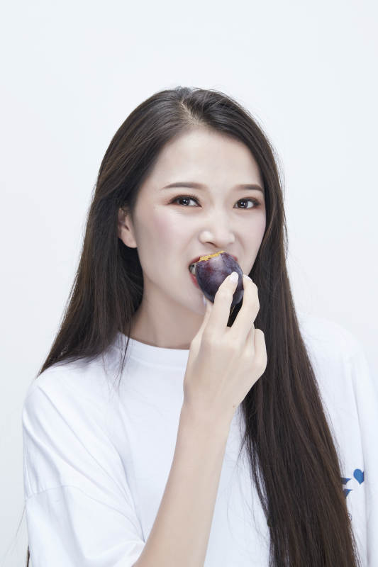 吃西梅的身穿白色长T血衬衫的长发少女人像图片