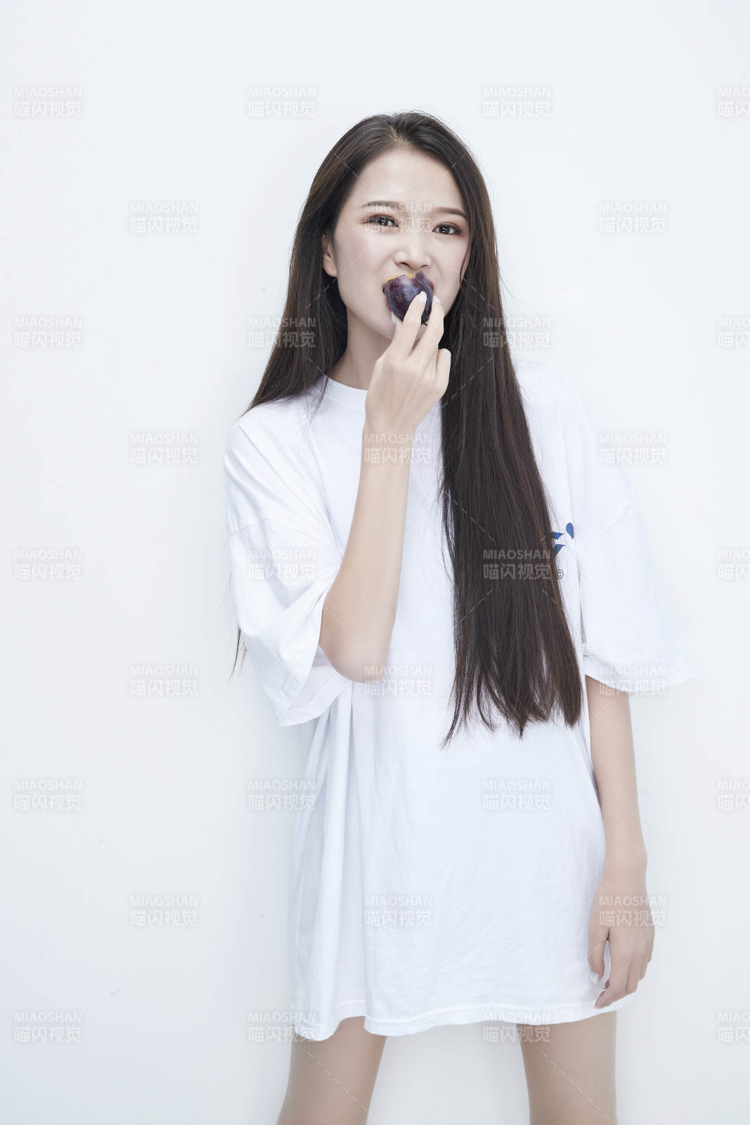 吃西梅的身穿白色长T血衬衫的长发少女人像图片