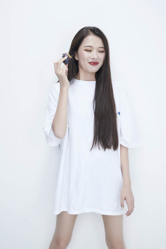 吃西梅的身穿白色长T血衬衫的长发少女人像图片
