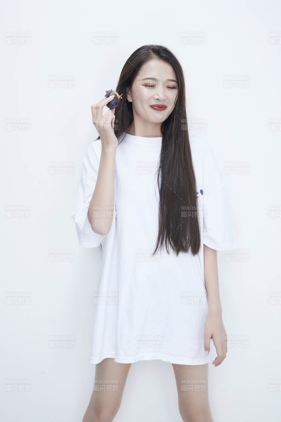 吃西梅的身穿白色长T血衬衫的长发少女人像图片