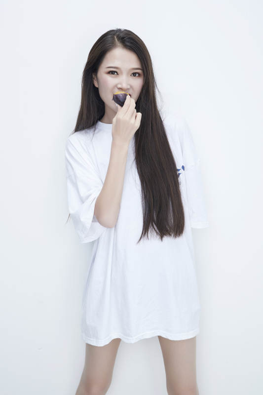 吃西梅的身穿白色长T血衬衫的长发少女人像图片