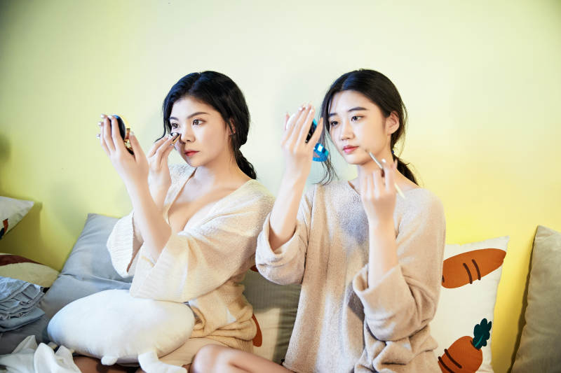 坐在床上化妆玩耍的俩位美女图片
