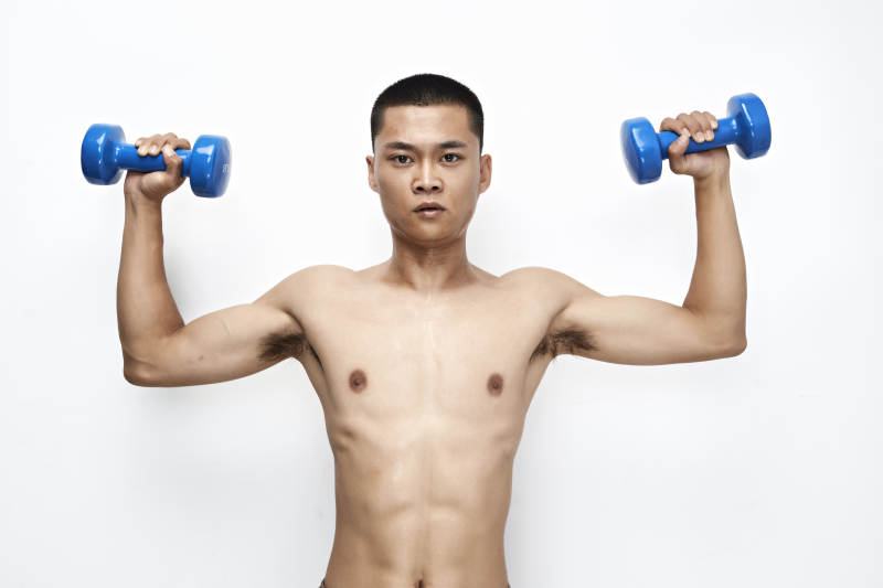 使用哑铃进行健身锻炼的亚洲男性图片