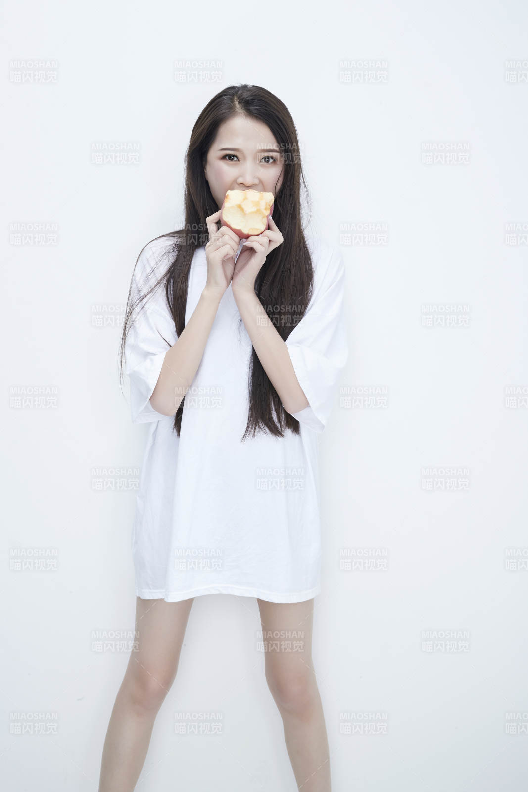 吃苹果的穿白色长T血衫的长发可爱少女人像图片