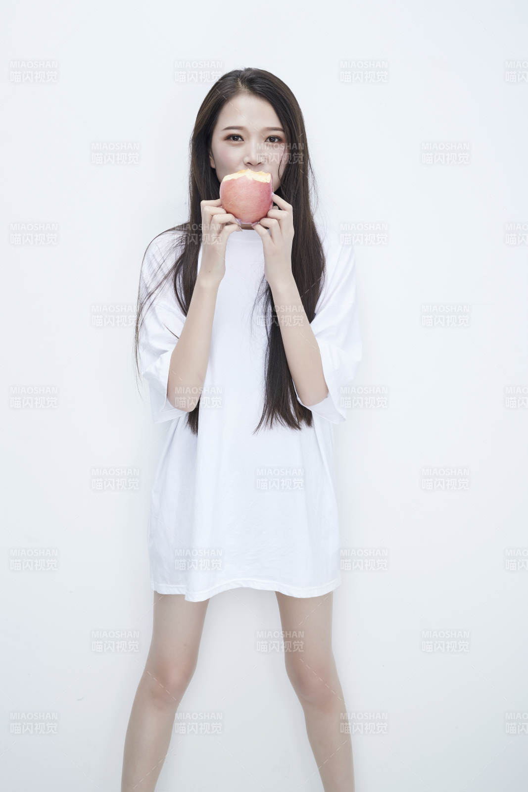 吃苹果的穿白色长T血衫的长发可爱少女人像图片
