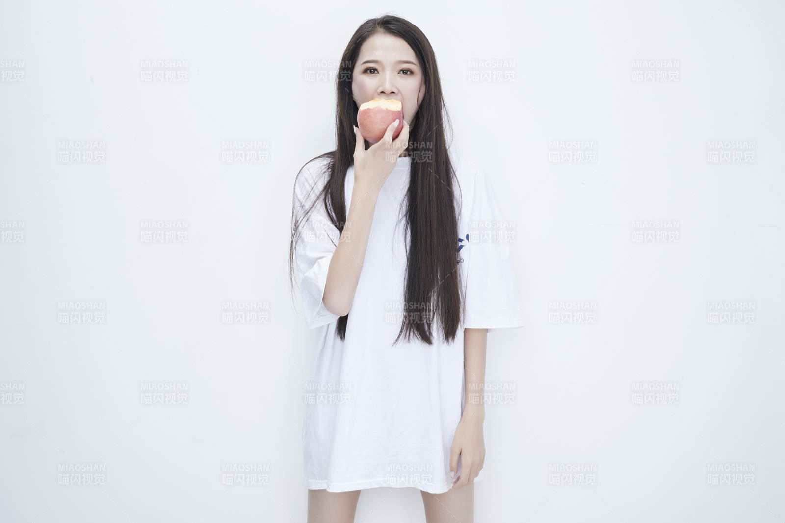 吃苹果的穿白色长T血衫的长发可爱少女人像图片