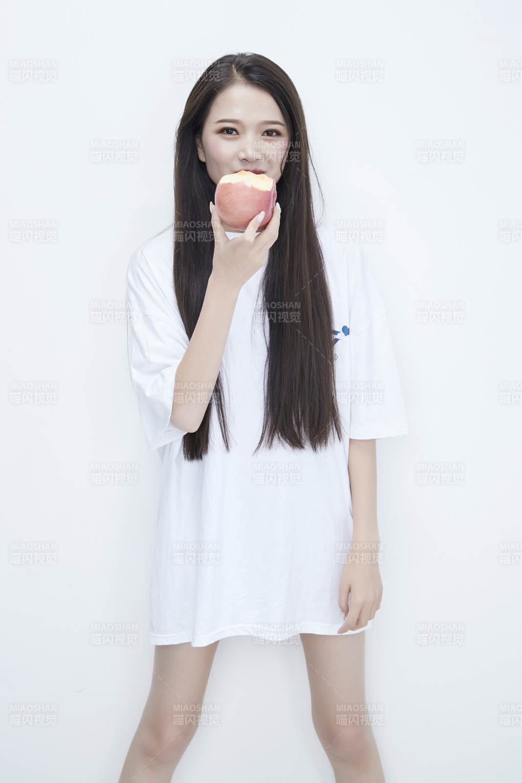 吃苹果的穿白色长T血衫的长发可爱少女人像图片