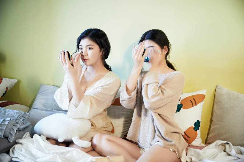 坐在床上化妆玩耍的俩位美女图片