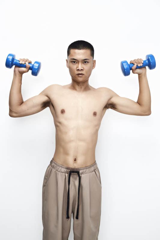 使用哑铃进行健身锻炼的亚洲男性图片