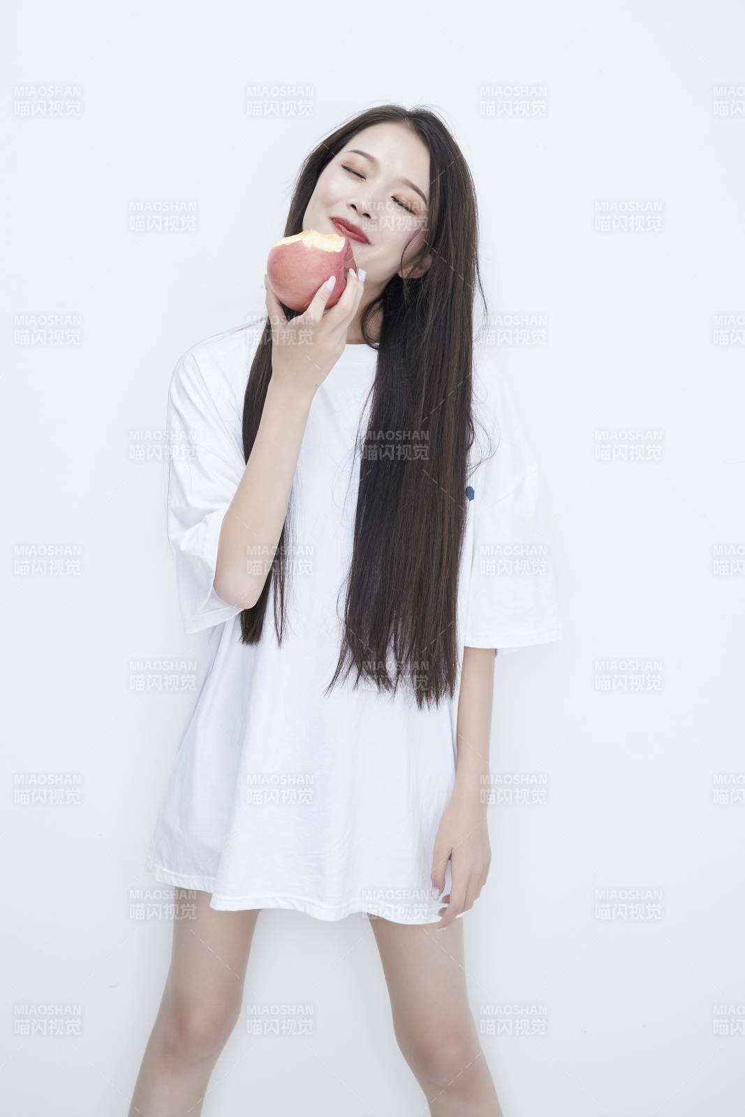 吃苹果的穿白色长T血衫的长发可爱少女人像图片