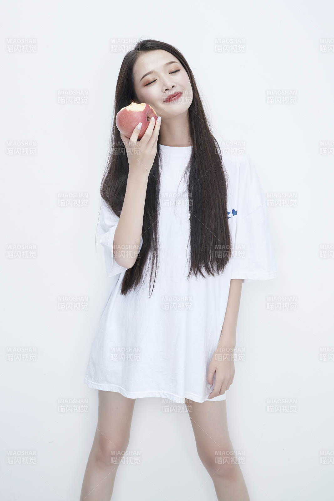 吃苹果的穿白色长T血衫的长发可爱少女人像图片