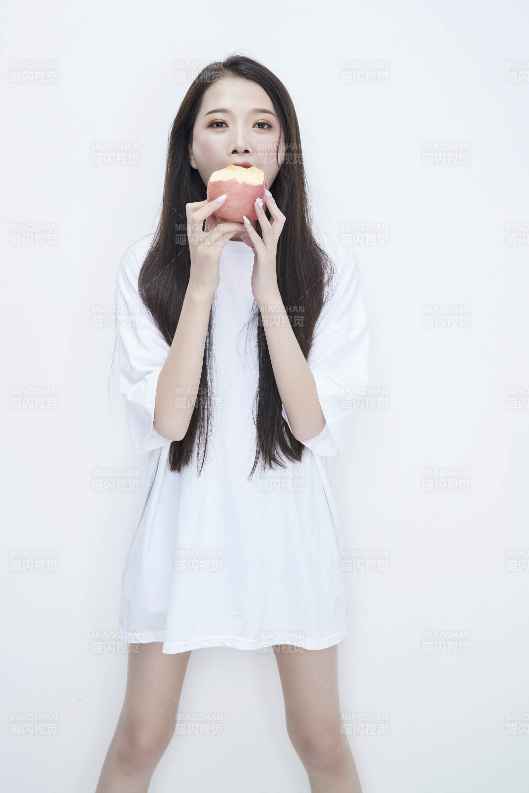 吃苹果的穿白色长T血衫的长发可爱少女人像图片