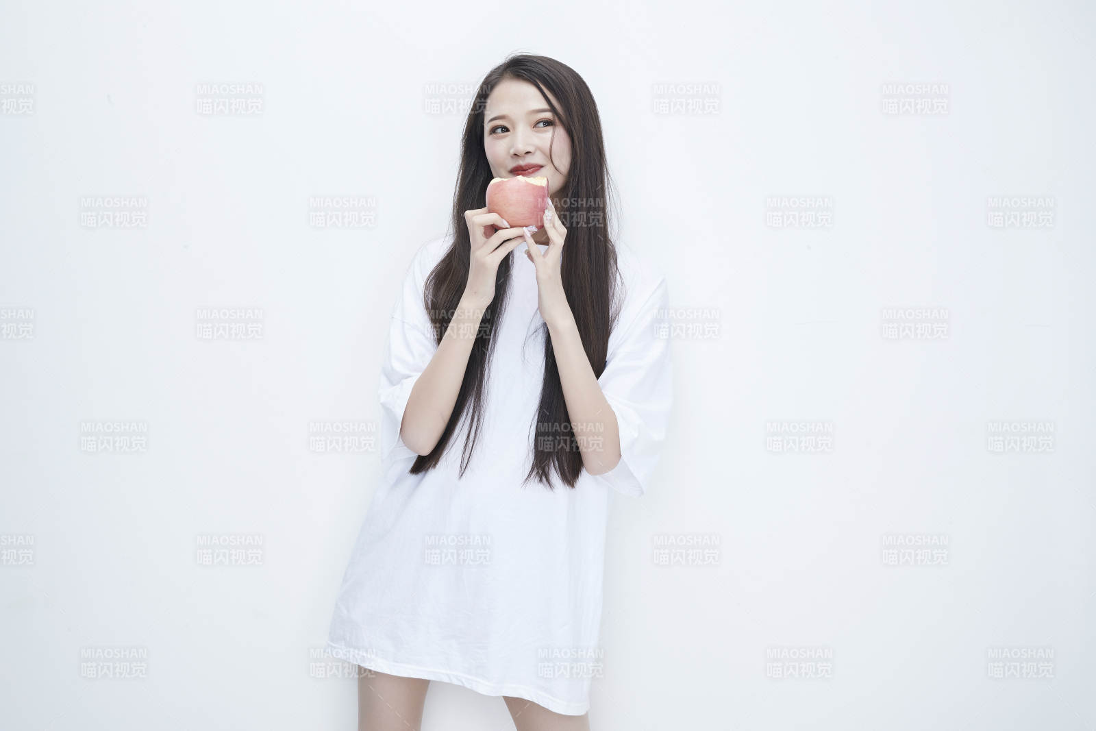 吃苹果的穿白色长T血衫的长发可爱少女人像图片