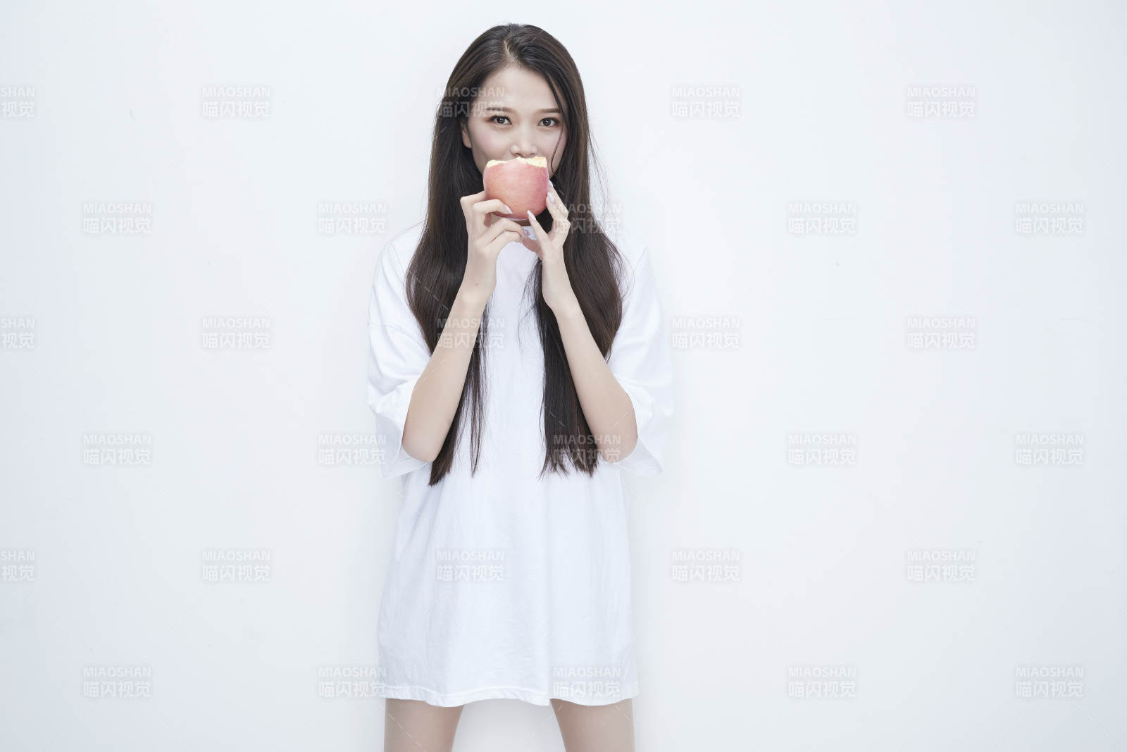 吃苹果的穿白色长T血衫的长发可爱少女人像图片