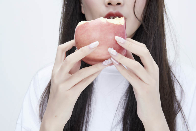 吃苹果的穿白色长T血衫的长发可爱少女人像图片