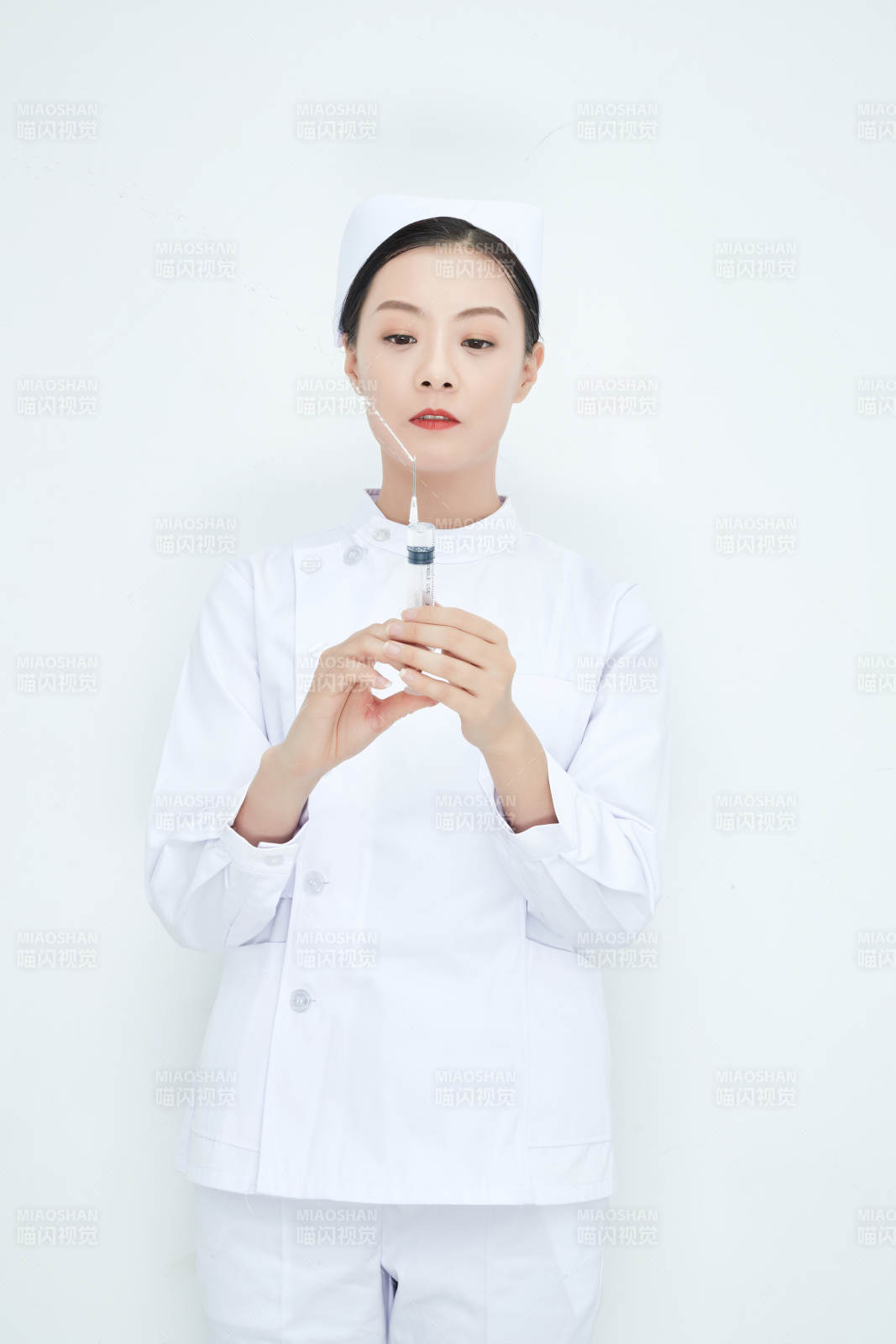 穿护士服戴口罩手执针筒的年轻女护士图片