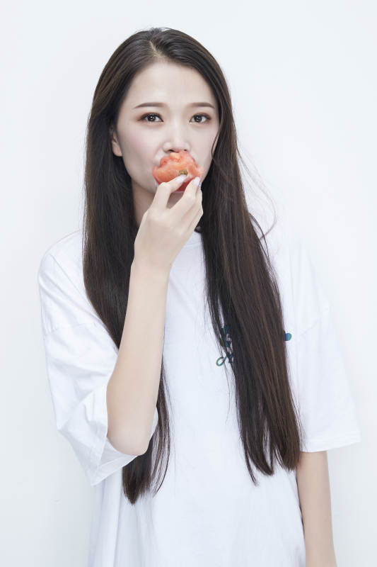 吃番茄的身穿白色长T血衬衫的长发少女人像图片
