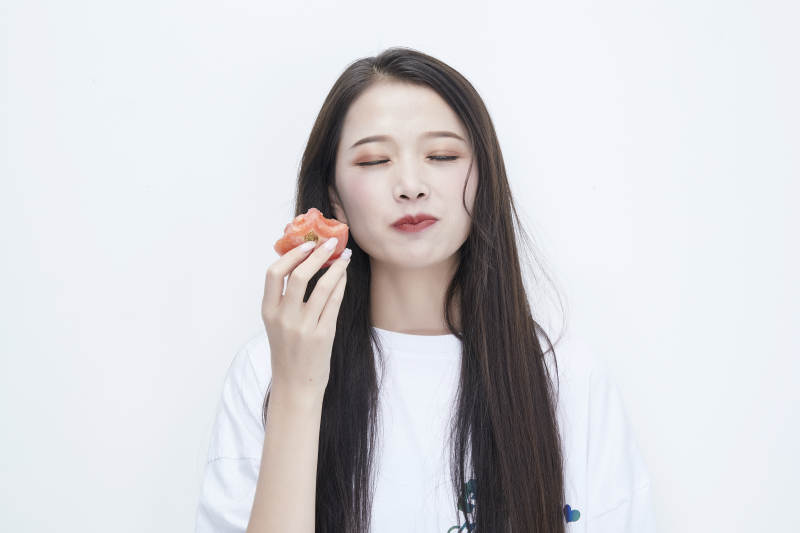吃番茄的身穿白色长T血衬衫的长发少女人像图片