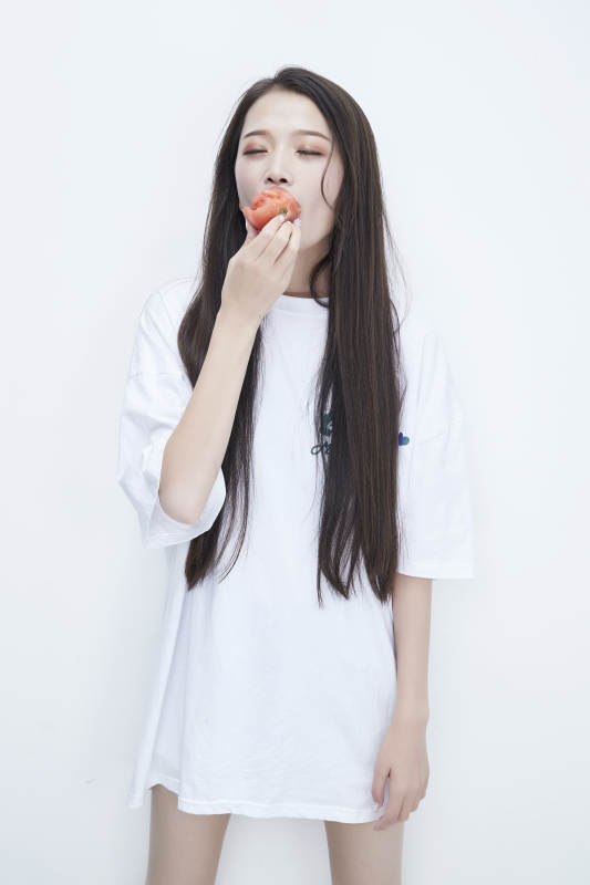 吃番茄的身穿白色长T血衬衫的长发少女人像图片