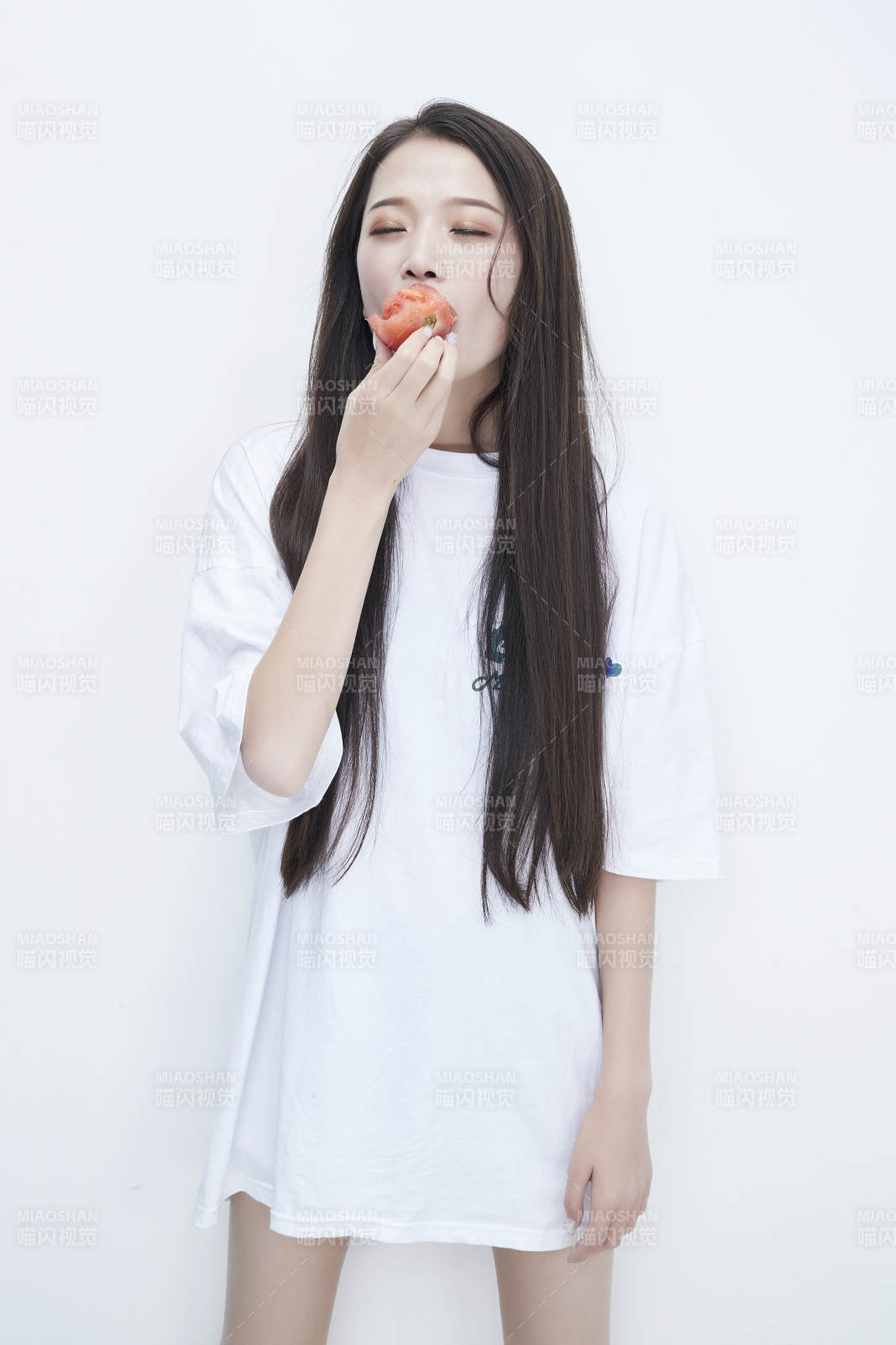 吃番茄的身穿白色长T血衬衫的长发少女人像图片