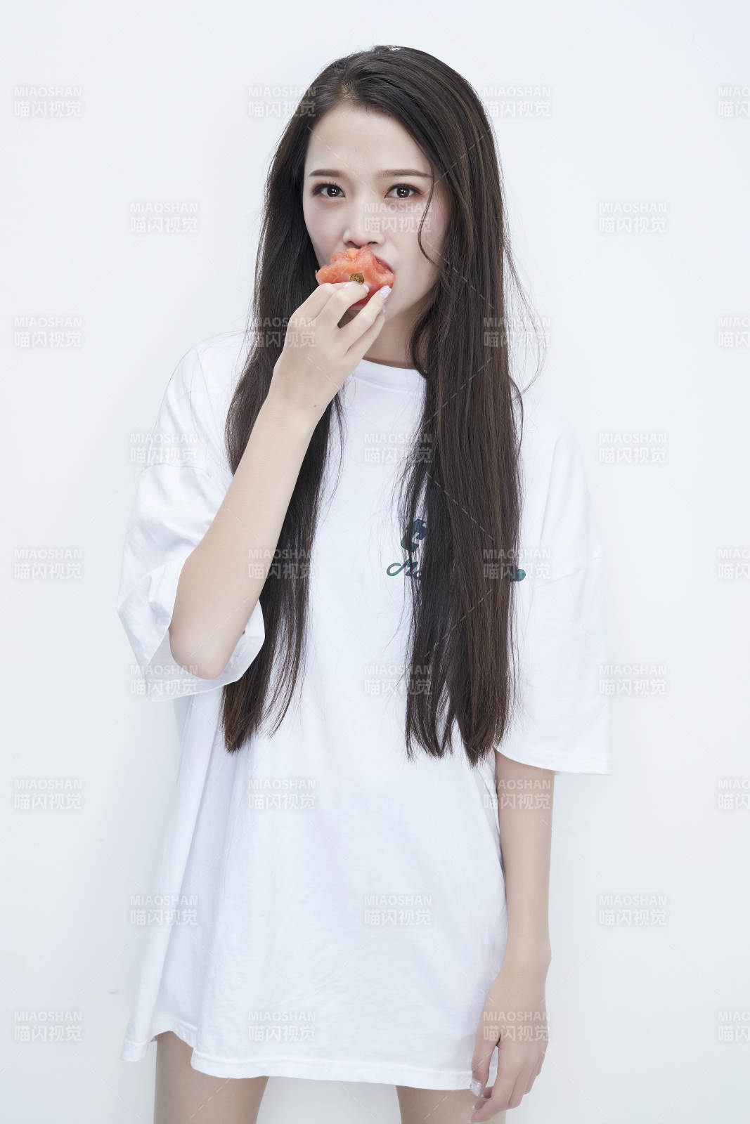 吃番茄的身穿白色长T血衬衫的长发少女人像图片