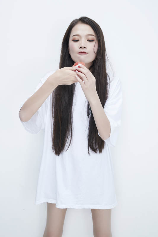 吃番茄的身穿白色长T血衬衫的长发少女人像图片