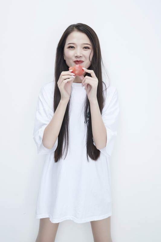 吃番茄的身穿白色长T血衬衫的长发少女人像图片