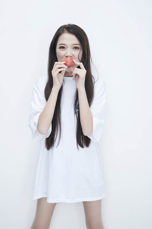 吃番茄的身穿白色长T血衬衫的长发少女人像图片