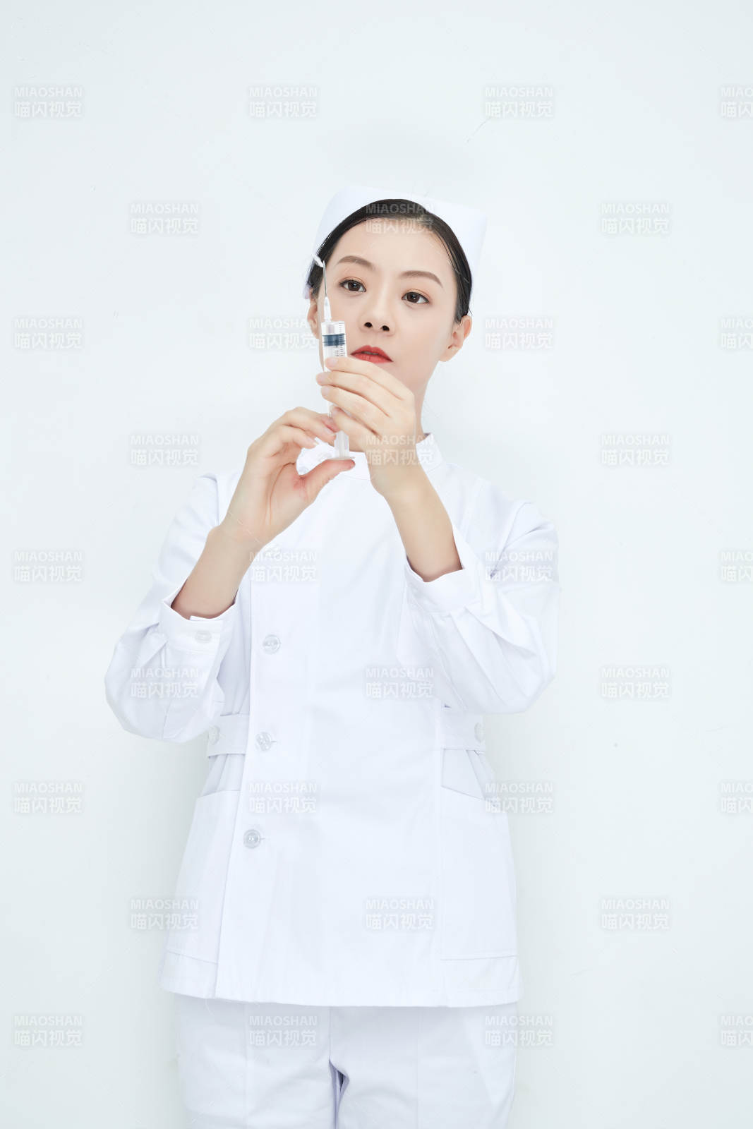 穿护士服戴口罩手执针筒的年轻女护士图片