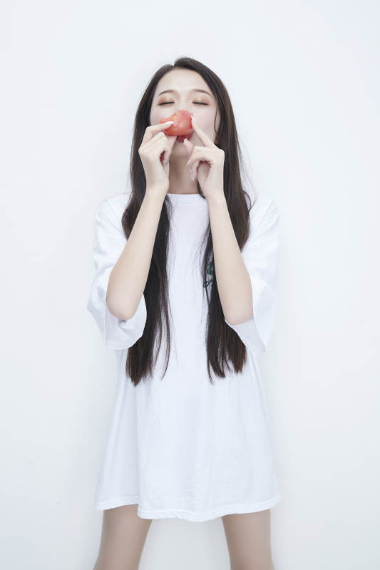 吃番茄的身穿白色长T血衬衫的长发少女人像图片