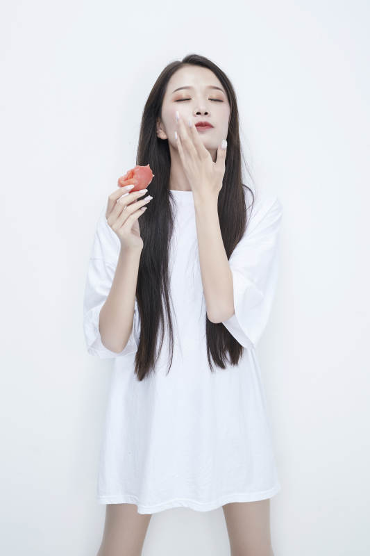 吃番茄的身穿白色长T血衬衫的长发少女人像图片