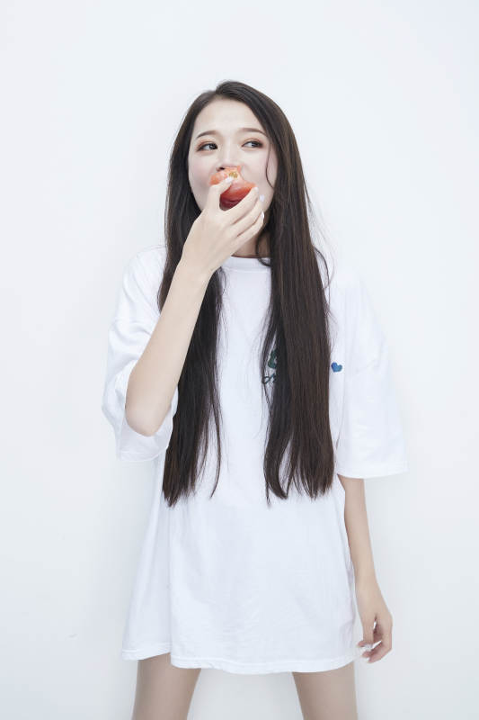 吃番茄的身穿白色长T血衬衫的长发少女人像图片