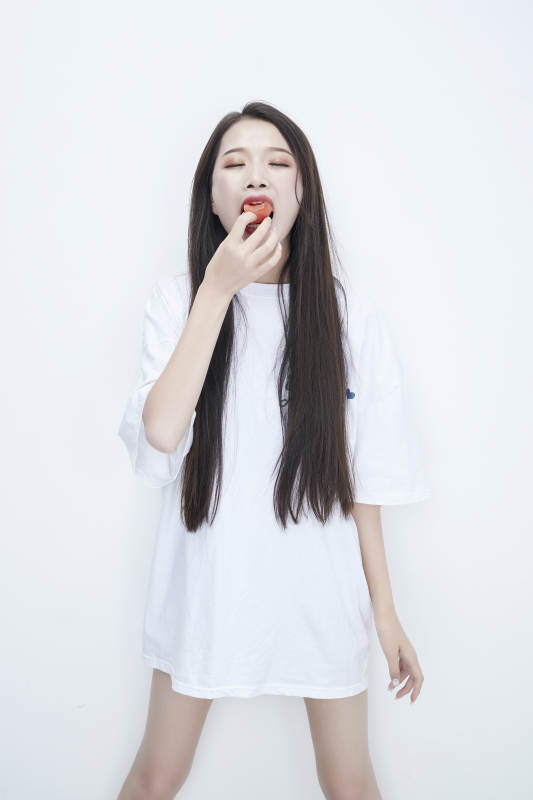 吃番茄的身穿白色长T血衬衫的长发少女人像图片