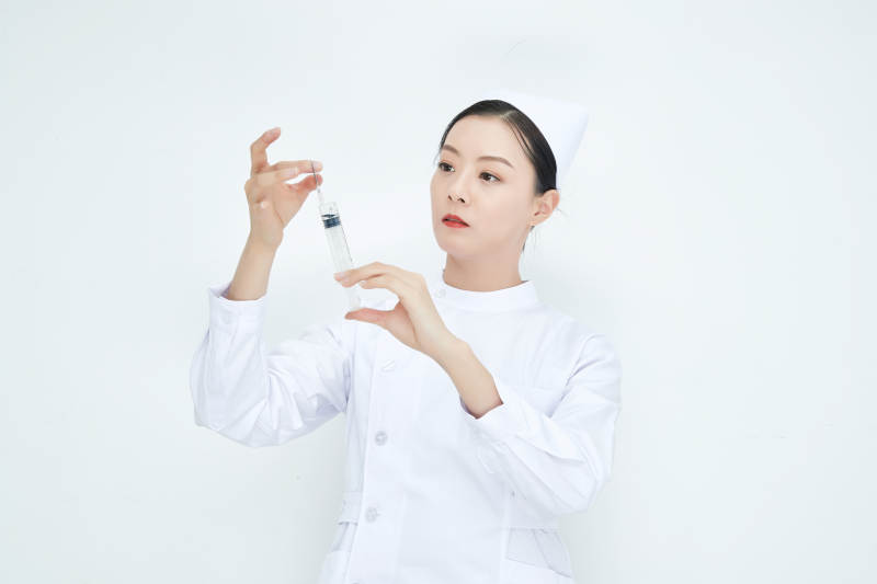 穿护士服戴口罩手执针筒的年轻女护士图片