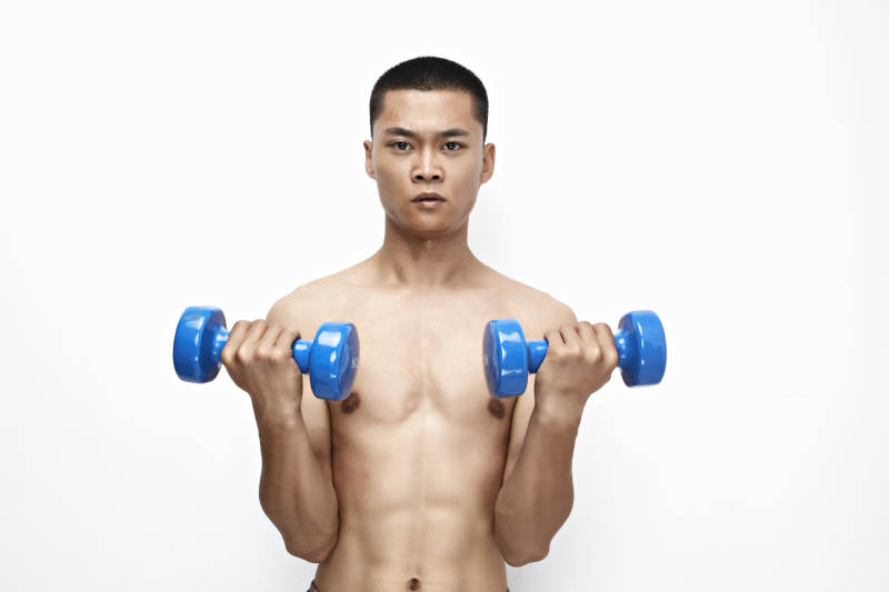使用哑铃进行健身锻炼的亚洲男性图片