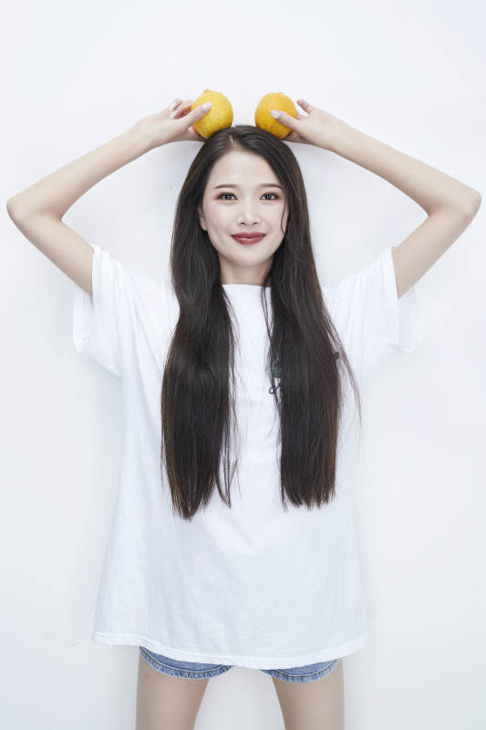 手拿柠檬身穿白色长T血的亚洲可爱少女人像图片